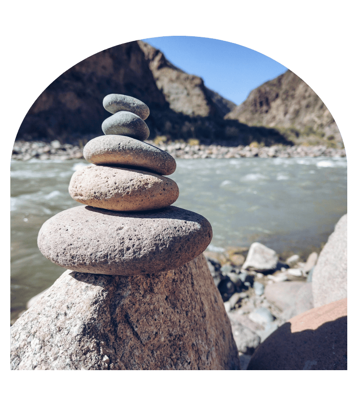 Empilement de galets en équilibre au bord d’une rivière, symbole d’harmonie et d’ancrage lors d’une séance de magnétisme.